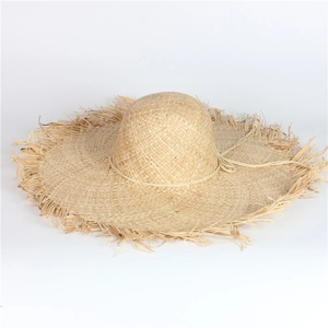 Close-up of a wide-brim raffia sun hat featuring raw fringe edges and woven texture