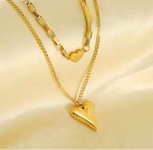 Detail of gold double-layered heart necklace on beige satin silk background
