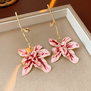 Macro view of vintage-style flower earrings featuring pink marble enamel and gold branches