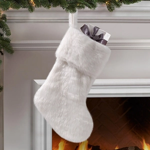 White plush Christmas stocking decoration hanging on a warm fireplace mantel