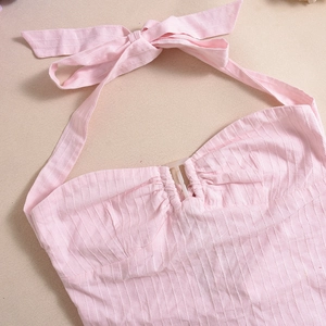 Dettaglio del top rosa con allacciatura al collo e trama del tessuto a pieghe