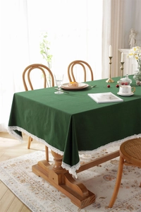 Close-up of dark green cotton tablecloth with delicate white lace border detail