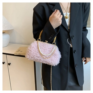 Pink plush shell bag with bamboo handle and pearl chain detail worn on model