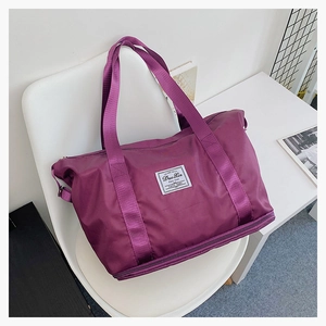 Close-up of a purple travel bag with a reinforced handle and branded woven label