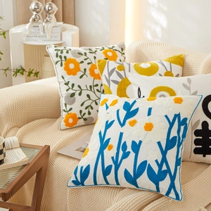 White cotton pillowcase with floral embroidery on a cozy beige knit blanket background