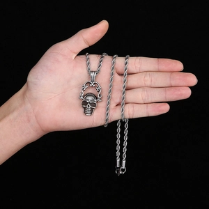 Vue détaillée du pendentif crâne de pirate en acier inoxydable tenu dans la main