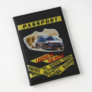 Detailed view of a black rally car design passport cover with warning tape patterns and text.