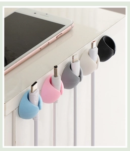 Close-up of colorful silicone cable organizers holding wires on a white desk edge