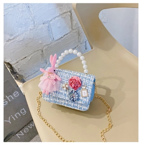 Detail of tweed girls' crossbody bag featuring pearl handle, pink bunny, and floral charms