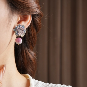 Détail d'une boucle d'oreille fleurie vintage avec rose mauve et perle de verre
