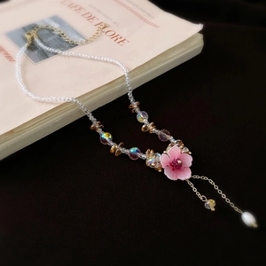 Elegant beaded necklace with pink flower, crystal beads, and a pearl tassel pendant