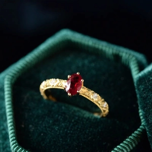 Macro shot of gold-plated silver ring with red oval gemstone on green velvet