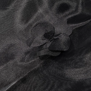 Détail rapproché d'une applique florale 3D sur un tissu en maille organza noir pour robe