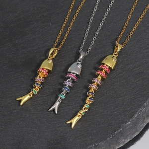 Macro view of articulated fish pendants with colorful zircons in gold and silver finish