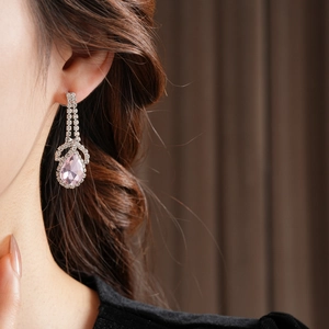 Detail of elegant silver drop earrings with pink pear-cut crystals on a female model