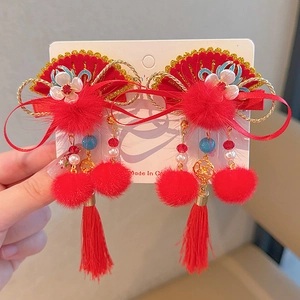 Detail of red Chinese New Year hair clips with gold fan, flower and long tassel on card
