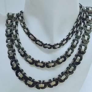 Macro detail of triple-layer silver and green woven chain necklaces for men on mannequin
