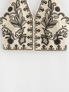 Detail of bohemian halter top featuring black floral embroidery and metallic sequins