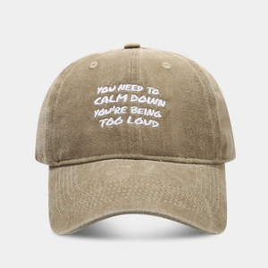 Detail of embroidered quote on washed khaki cotton baseball cap with vintage finish