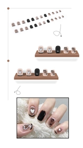 Detail of short almond black and white heart press-on nails with dot patterns