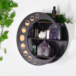 Moon-shaped wooden shelf with moon phase accents holding crystals and essential oils