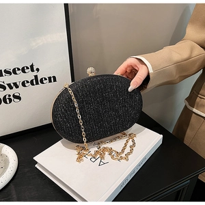 Detail of elegant black glitter clutch bag with gold trim and crystal sphere clasp