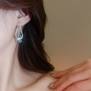 Detail of drop-shaped blue crystal earrings with sparkling rhinestones on female model