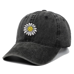 Macro detail of white daisy embroidery on vintage black washed denim baseball cap