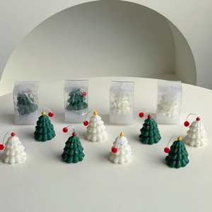 Detailed view of mini Christmas tree candles in dark green and cream with gift boxes