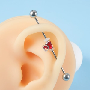 Detail showing an industrial barbell with a red heart zircon and small heart charm