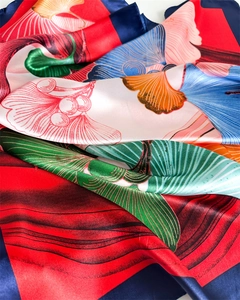 Close-up of satin silk scarf featuring vibrant ginkgo leaves and geometric pattern