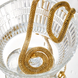 Minimalist gold stainless steel mesh chain necklace shown in a crystal clear glass of water