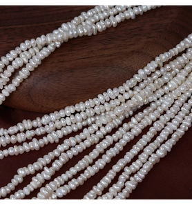 Vue détaillée de perles d'eau douce naturelles blanches de 4mm sur bois sombre et tissu