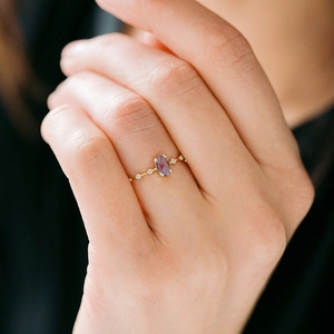 Elegant 18k gold ring featuring oval purple gemstone and white diamond accents