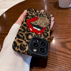Leopard print iPhone case with bold red lips design held over a wooden table