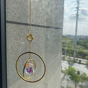 Golden suncatcher with eye metal frame and crystal prism reflecting rainbow light