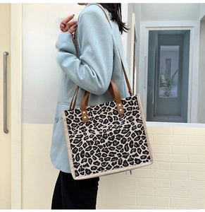 Chic leopard print linen tote bag with brown leather handles worn by a model in office