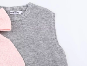 Detail of grey knitted vest neckline with fine ribbed edges and premium brand label