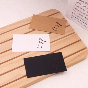 Three-color smiley face cardstock earring display cards on a wooden stand
