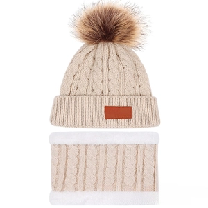Detail view of beige cable knit toddler hat with fur pompom and fleece-lined neck warmer