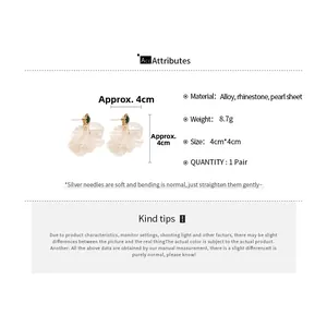Detail of petal tassel earrings with rhinestones and pearls on a white background