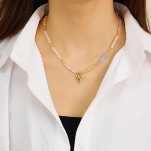 Detail of bohemian colorful beaded necklace with a golden heart pendant on a model