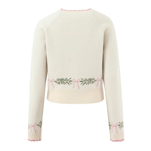 Back view of cream knit cardigan with pink wavy trim and floral bow jacquard pattern