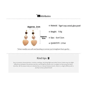 Detail showing vintage wood heart earrings with tiger eye stone and glass pearl accents