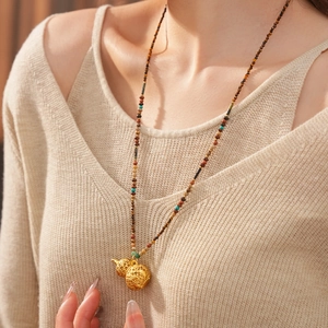 Detailed close-up of a hollow gold gourd pendant necklace with multicolored beads