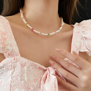 Minimalist pearl necklace with colorful stones on model wearing pink floral top