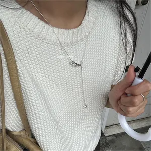Detailed view of a silver 925 beaded tassel necklace on a white knitted sweater
