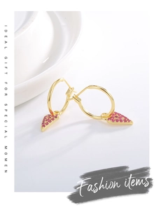 Detail view of gold earrings with triangular pendants set with sparkling magenta zircons