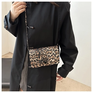 Close-up of leopard print square bag featuring a metallic chain strap and secure lock