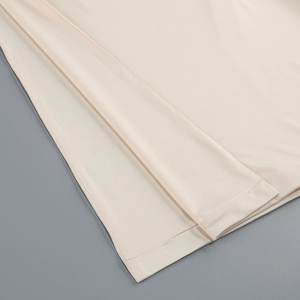 Detail view of double-needle hem on beige fishtail dress with premium knit fabric texture